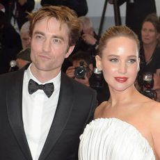 Robert Pattinson wears a tuxedo on the Cannes Film Festival red carpet as he poses next to Jennifer Lawrence, who is wearing a white custom Dior gown