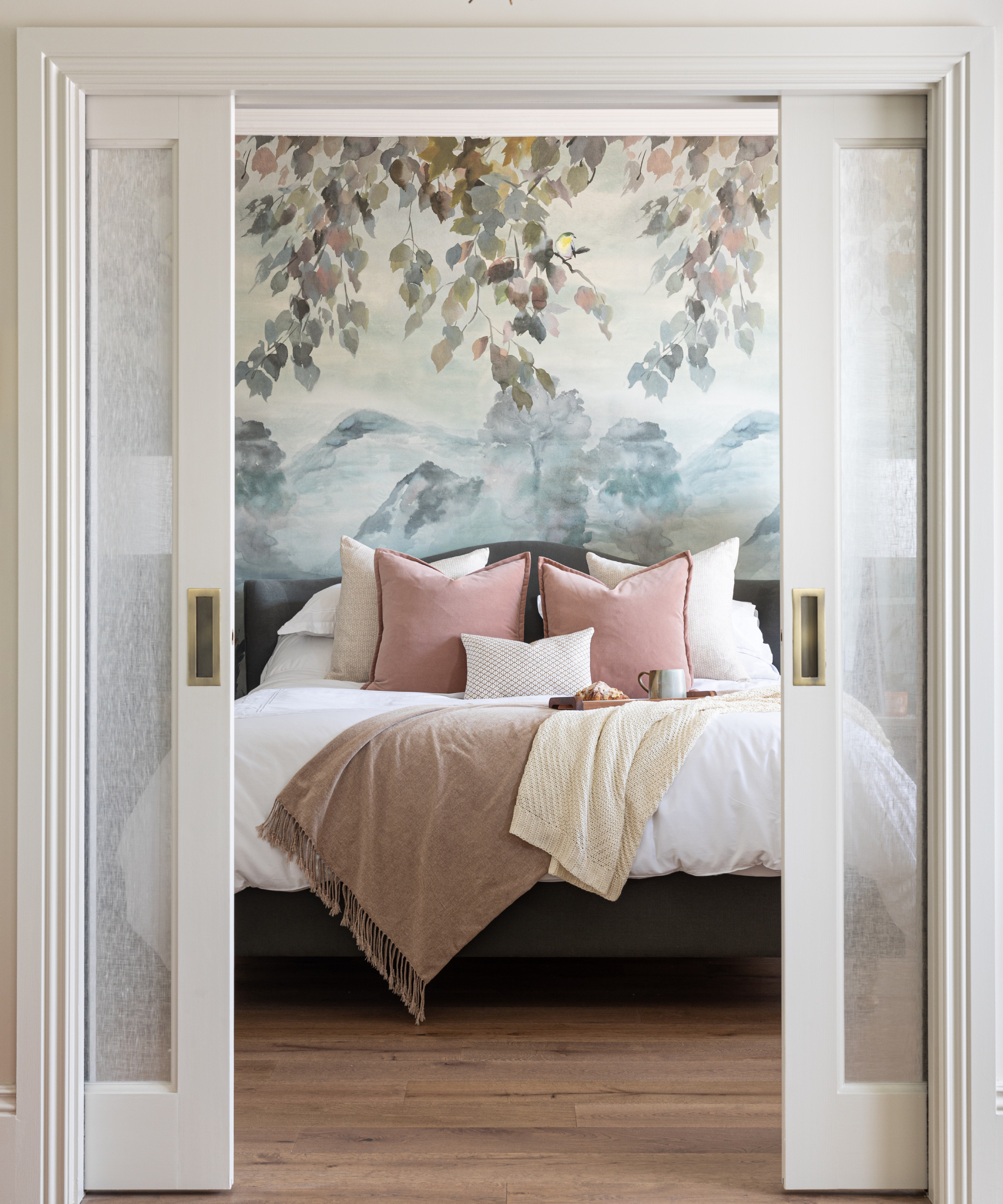 bedroom accessed via sliding pocket glass doors with nature inspired wallpaper and colour scheme of soft blues, pinks and creams