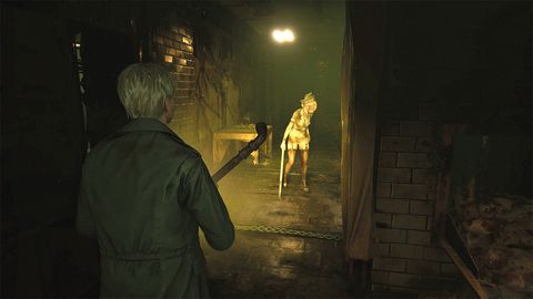 Silent Hill 2 review; a man holds a pipe and walks down a dark corridor