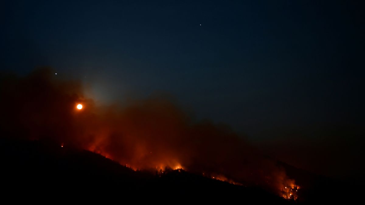 Jupiter and Saturn are seen as the full moon rises over a burning hillside in the Sequoia National Forest near Lake Isabella, in Kern County on Aug. 21, 2021 where the French Fire continues to burn in a heavily wooded area with 12,037 acres burnt and evacuation orders in place for nearby residents.
