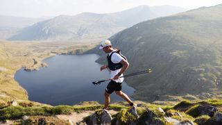 A trail runner on a ridge in Snowdonia, Eryri with lake in background