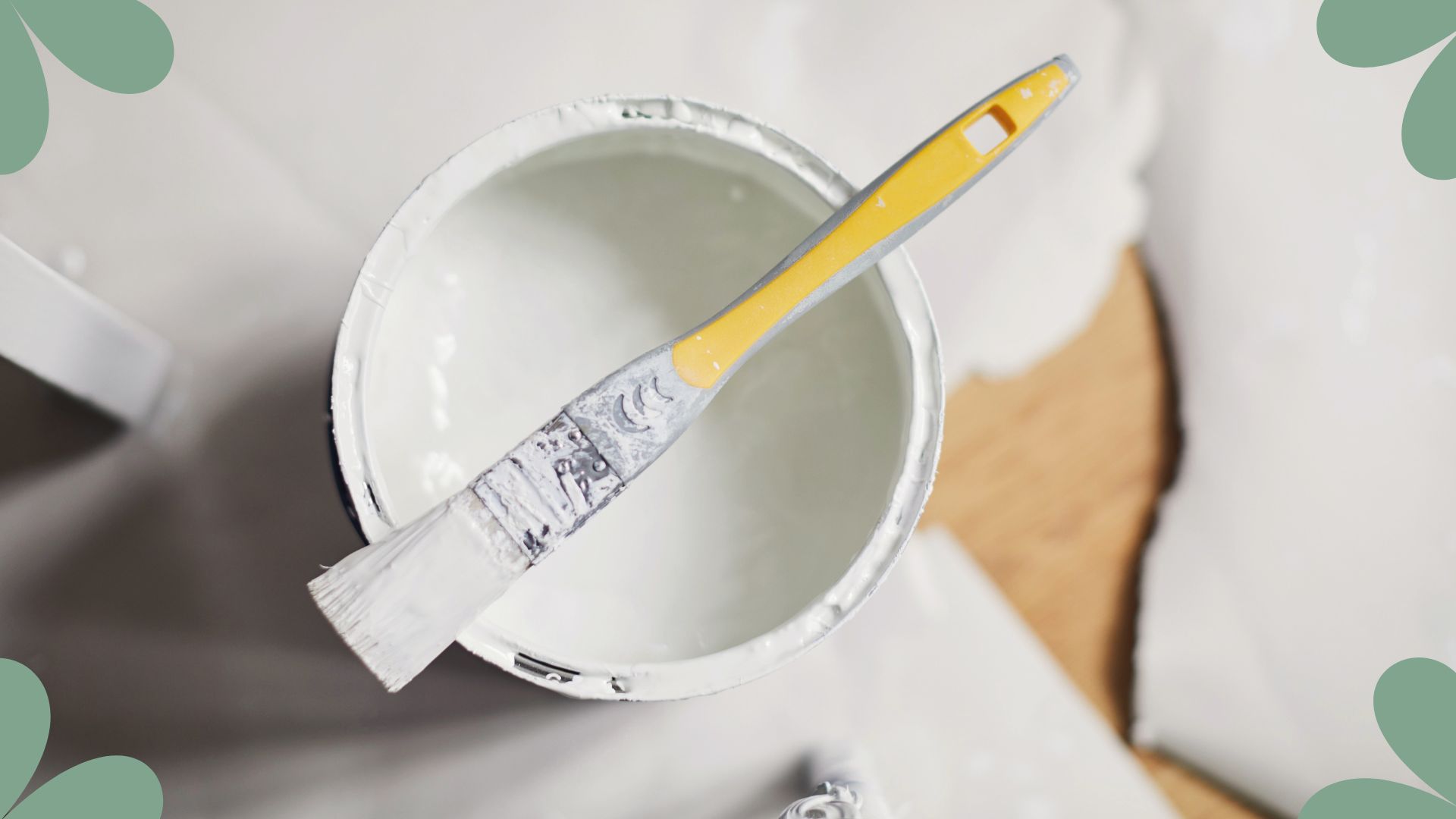 picture of white paint can with brush lent on top 
