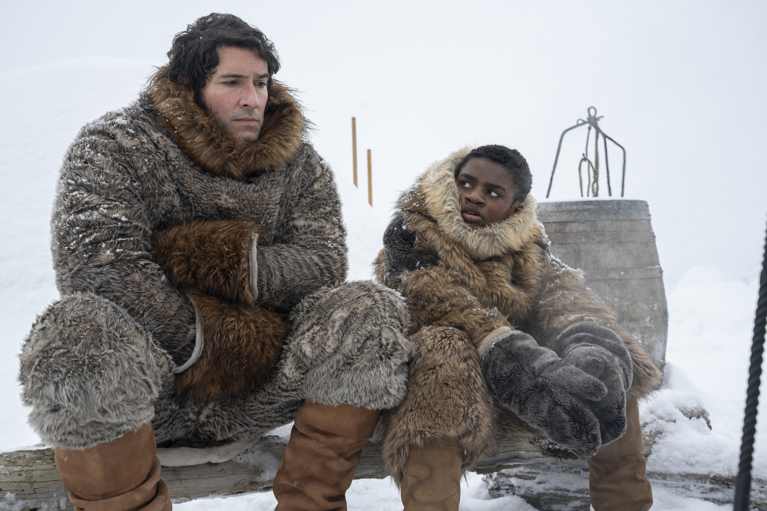 A man and a boy sit outdoors in the Arctic, in 'Washington Black.'
