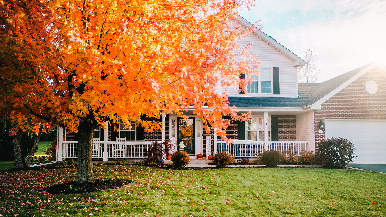 Exterior of an american house surrounded y fall foliage ahead of the first frost