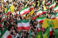 Iranians wave Iran’s national flags during a rally. (Photo by AFP) /