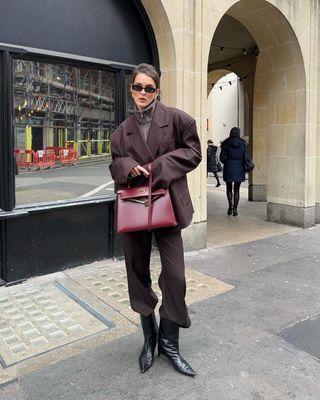 Boot Trends 2024: @sobalera wears black kitten heel boots with a burgundy suit