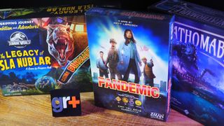 Jurassic World: The Legacy of Isla Nublar, Pandemic, and Unfathomable on a wooden table alongside a GamesRadar+ logo