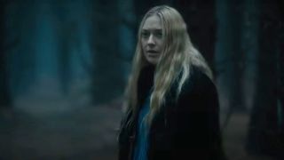 Mina (Dakota Fanning) looks over her shoulder as she walks through a forest in The Watchers. 
