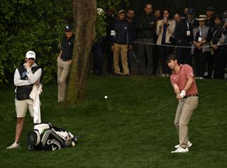 Ollie Schniederjans hits a chip shot with Greg Norman watching on close behind