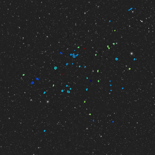 a view of a patch of space, with dozens of distant newfound galaxies circled in blue and green.