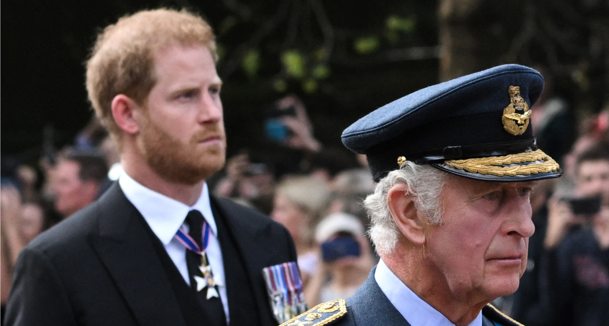 Prince Harry walking behind King Charles, who is wearing a military uniform