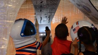 Museum visitors enter a packing tape replica of the Gemini capsule. Tape Gemini, along with another project Tape Wormhole, made their debuts at the Liberty Science Center on June 25.