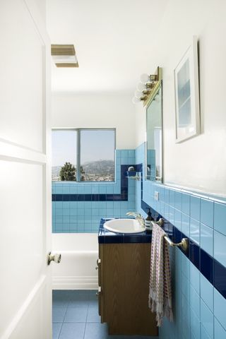 A bathroom with a wooden vanity and blue tiles with a strikethrough pattern