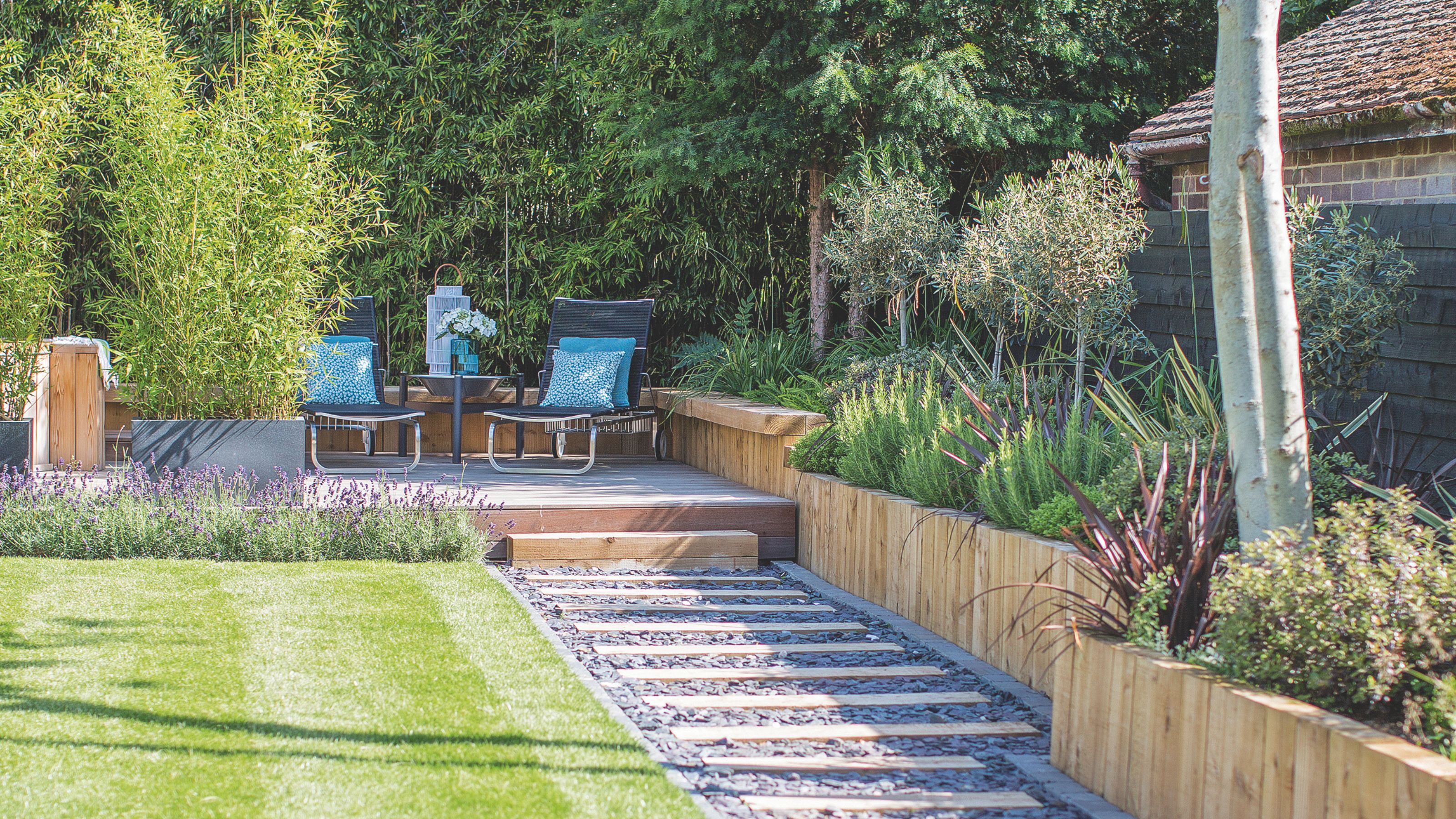 Decked pathway with gravel leading to decking area bordered by lavender plants