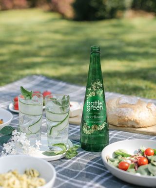 Picnic in garden with green glass bottle in centre bottlegreen