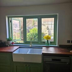 green windows in green kitchen with belfast sink and wood worktop
