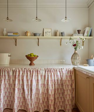 curtain skirt run along length of worktop tiled with cream tiles