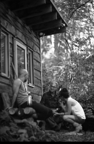 Larry Fink talking to two people outside a cabin