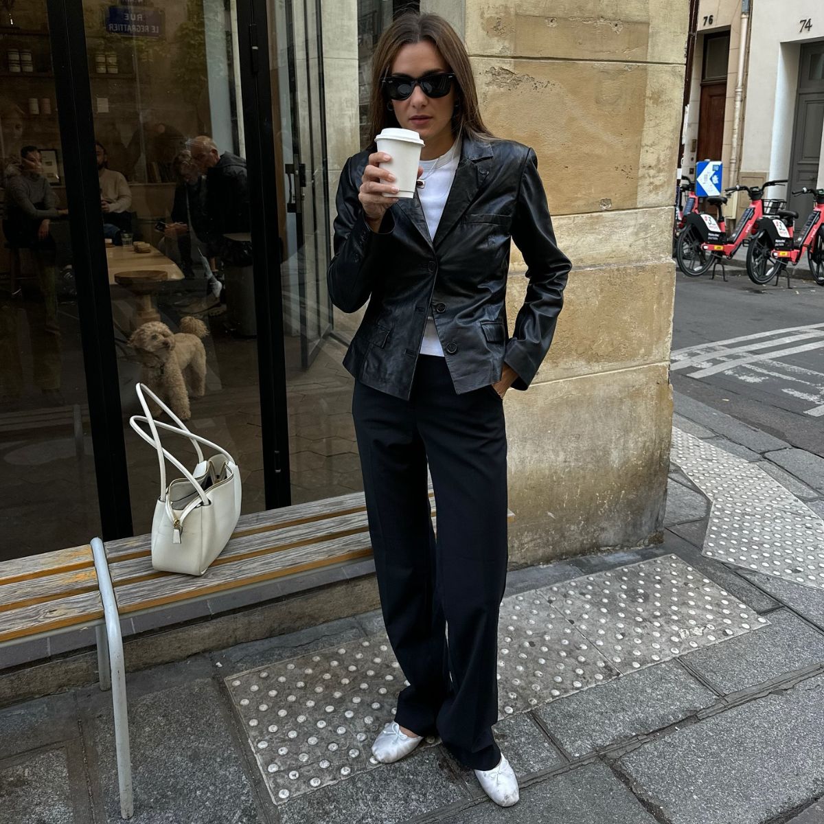 An image of @annelauremais wearing cigarette trousers with a leather jacket and white satin ballet flats. 