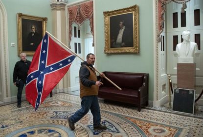 Man walks through Capitol with Confederate flag
