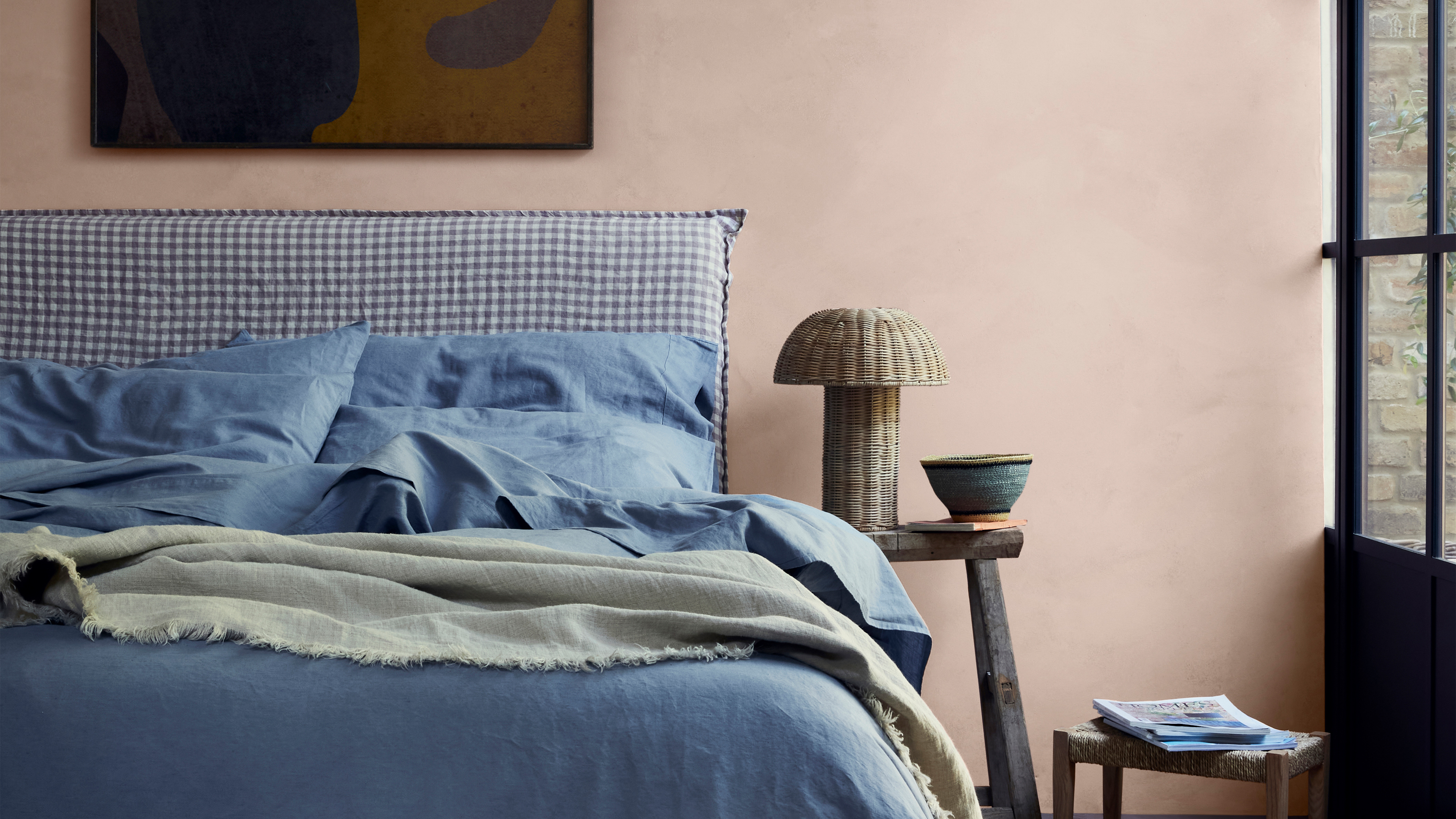 A bedroom with a blue bed and pink walls