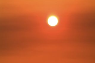 The sun burns through a fog of orange haze.