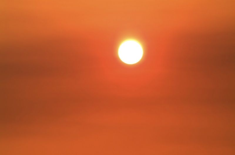 The sun burns through a fog of orange haze.