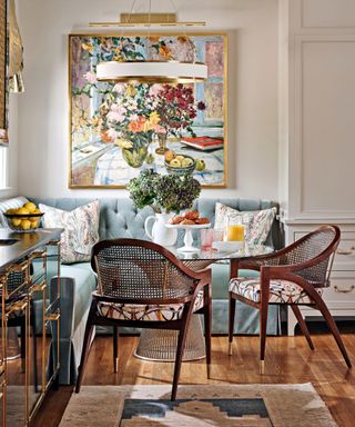 dining area with inbuilt blue velvet bench and cane chairs and art on wall