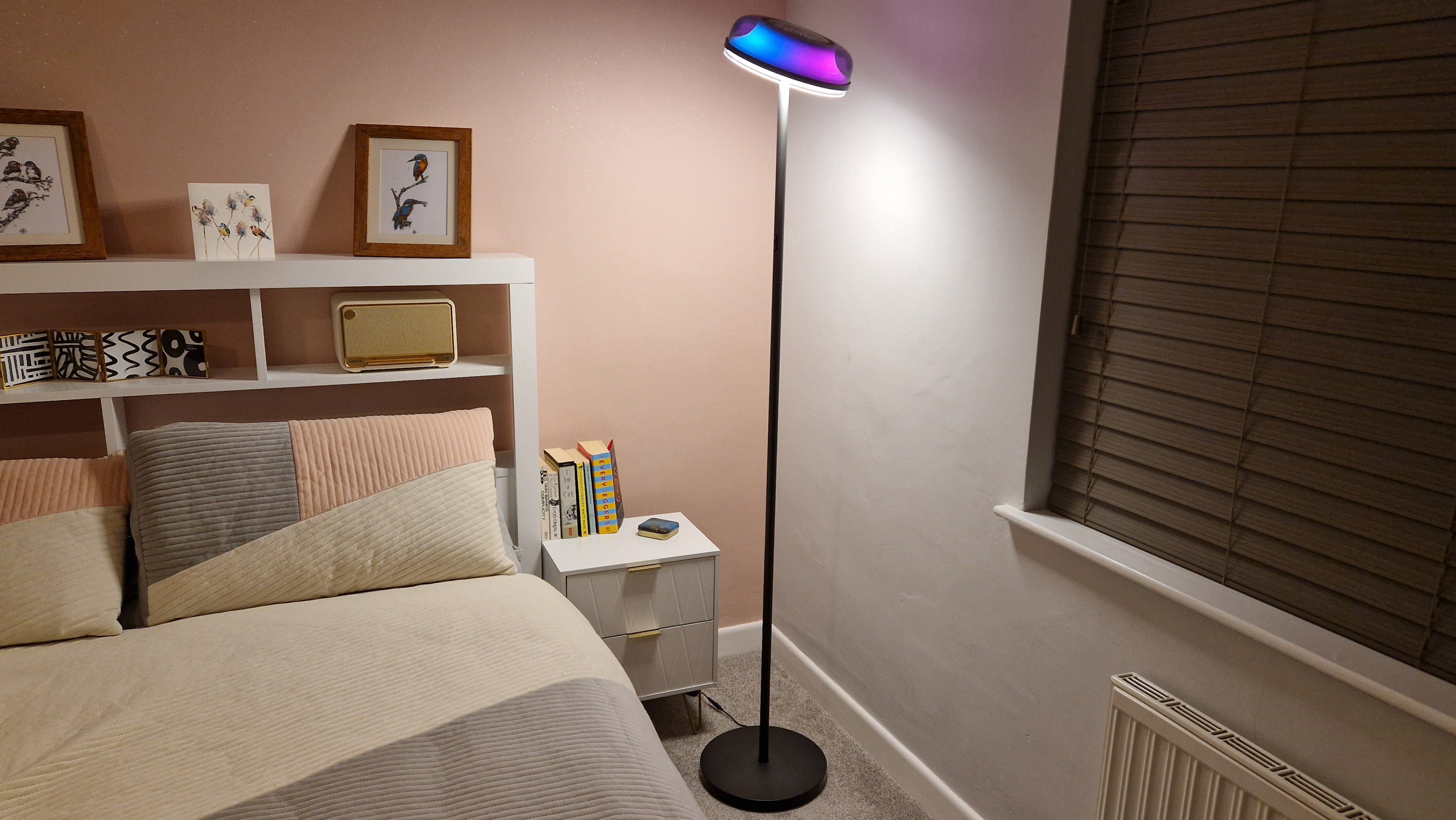 The base light of the Govee Uplighter Floor Lamp shines down onto a bed and night stand.