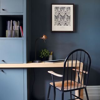 Desk and chair next to dark blue painted wall