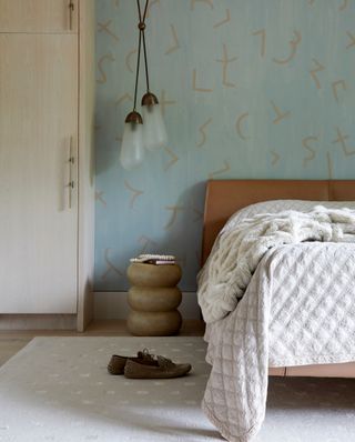 son's bedroom with leather bed, aqua patterned wallpaper, pendant lights and closet