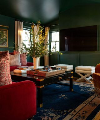 Dark green living room with red accent chairs