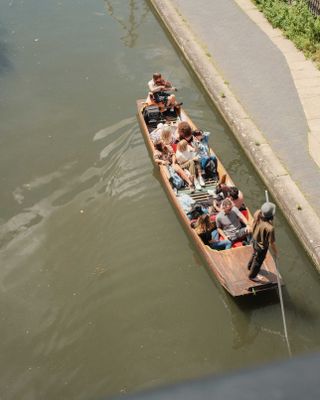 Gondola boat full of people going down a sunny canal in London