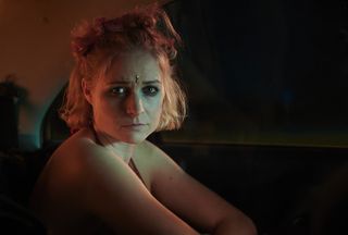 Niamh Algar in character as 'Sadie Byrne' in C4's Deceit, sitting at a bar and wearing glittery make-up as part of a previous undercover sting