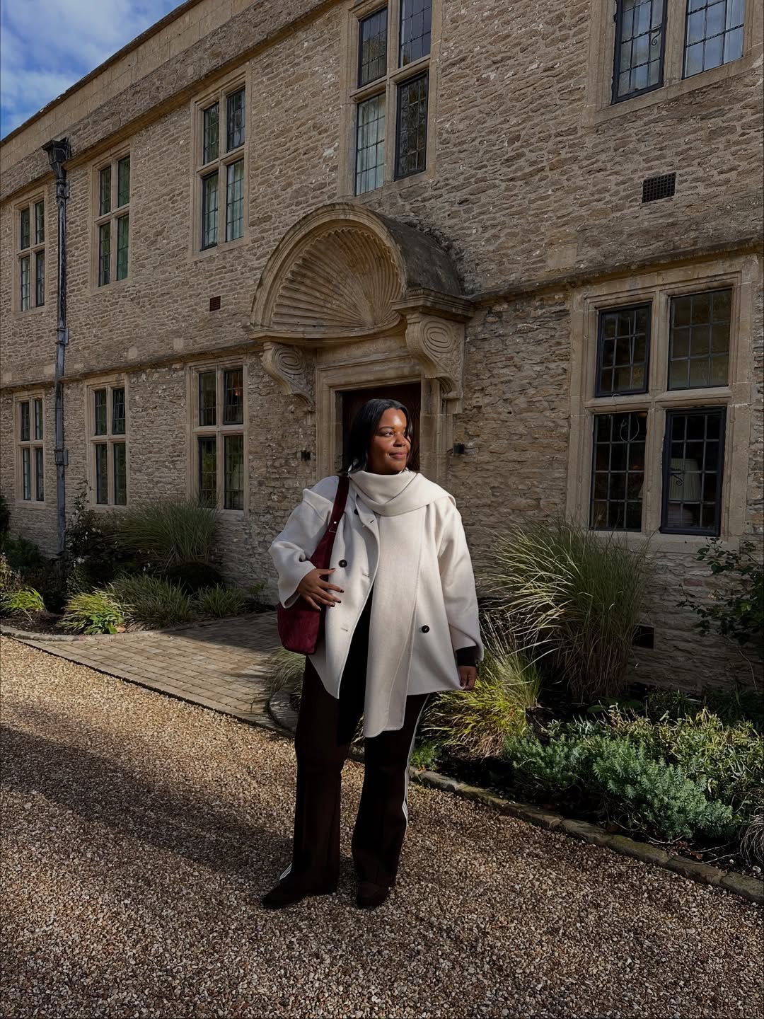 Karina in a scarf, coat, and striped trousers