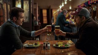 Jason Sudeikis as Ted and Brendan Hunt as Coach Beard toasting pints in the pub