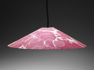 Shown on a black background, a red and white marbled lampshade made by Granby Workshop and Assemble