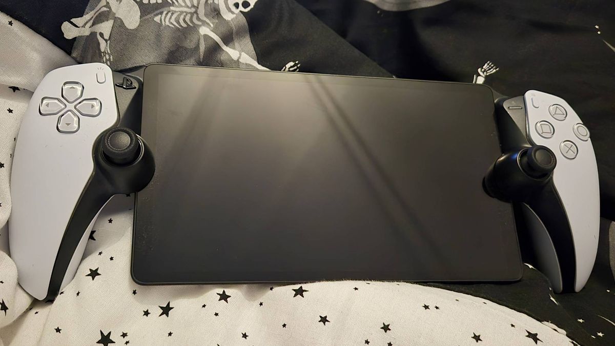 Image of the PS Portal with its screen turned off sitting on a black and white bed-cover set with a star print.