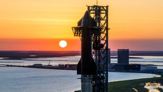 A SpaceX Starship rocket atop its booster at launchpad with the setting sun for Flight 6.