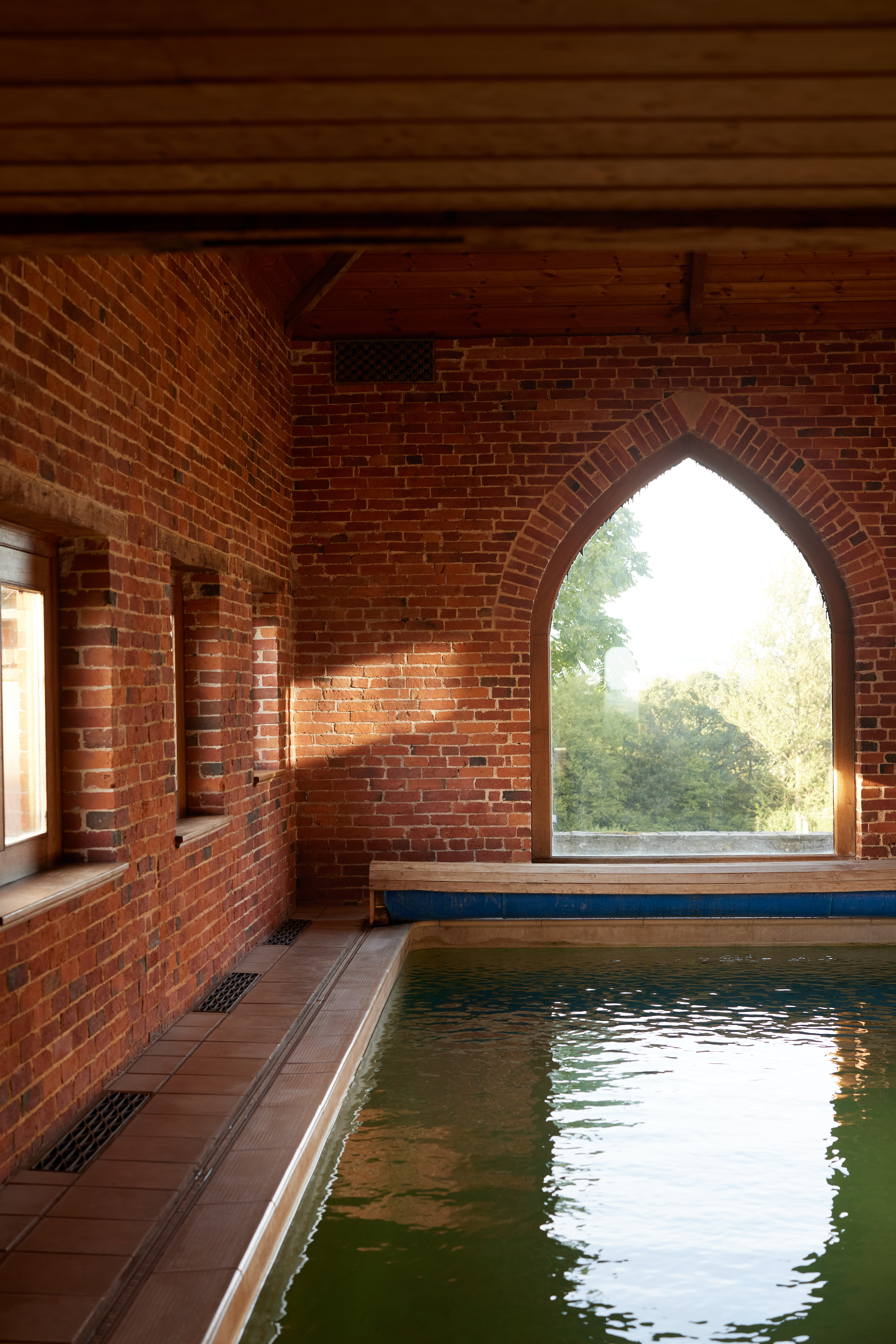 A former farm building has been converted into an indoor heated pool surrounded by red bricks and leafy views.