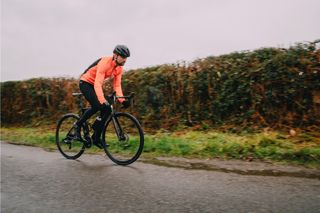 Image shows a rider wearing a winter jacket while cycling in the rain.