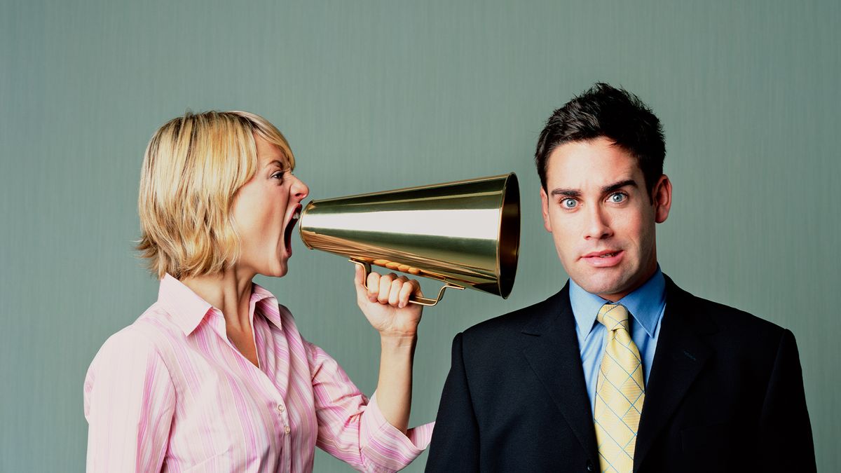 Female office worker shouting in a colleague&#039;s ear using a megaphone.