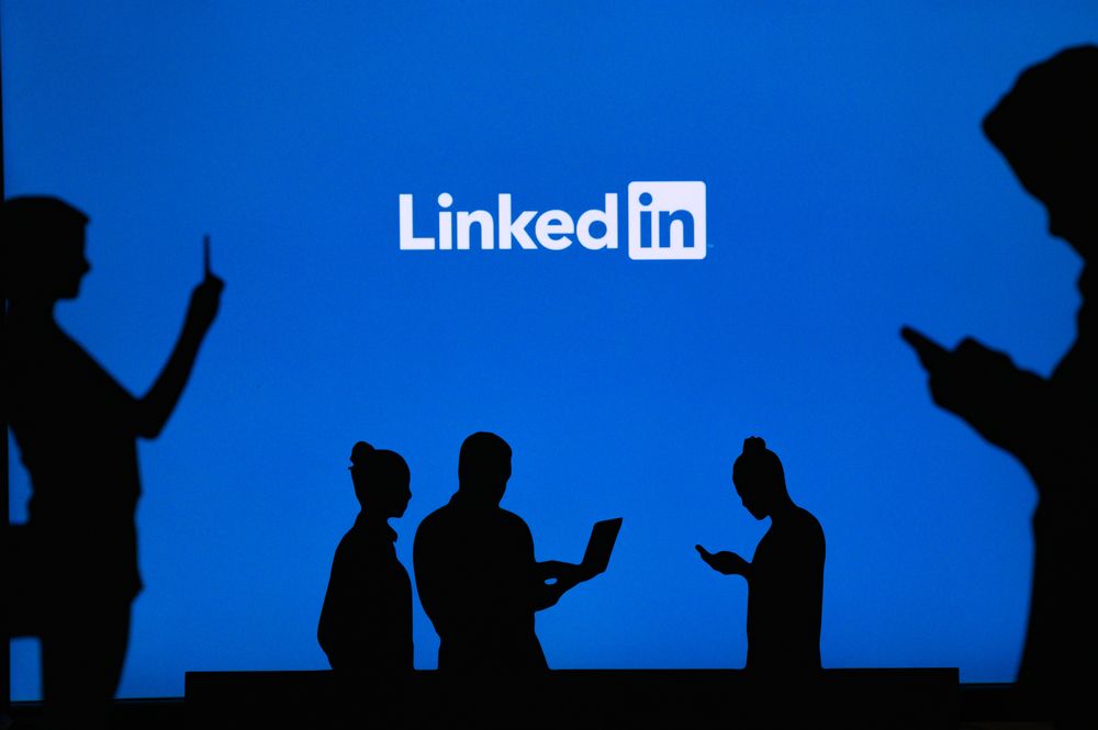 Shadows of people using phones in front of a LinkedIn sign