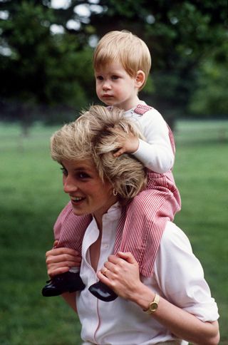 Princess Diana with a very young Prince Harry on her shoulders.