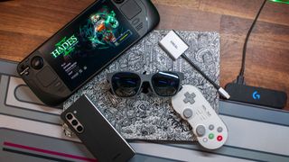 Top-down view of Xreal Air 2 smart glasses surrounded by Steam Deck, 8BitDo Controller, Galaxy Z Fold 5, and MacBook Pro