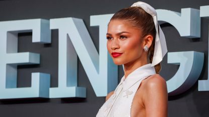 Zendaya wears a white Thom Browne dress with a matching hair ribbon on the Challengers London premiere red carpet