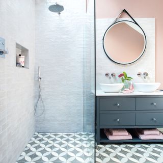 Wet room with tiled walls and floors and round mirror over vanity unit