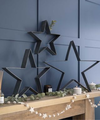 Christmas Mantel with blue walls and leaning black iron stars
