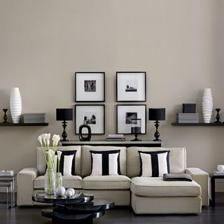 monochrome modern living room with neutral sofa black side table black shelves and black framed pictures