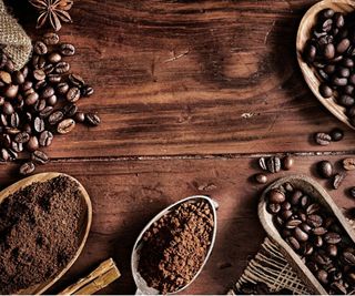 Coffee beans and grounds in scoops on a wooden table